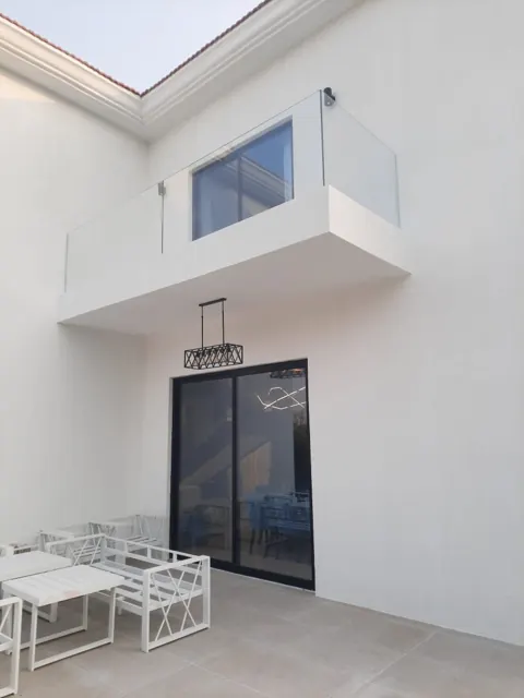 Balcony glass and patio doors: Clear balcony glazing above dark-framed sliding patio doors.