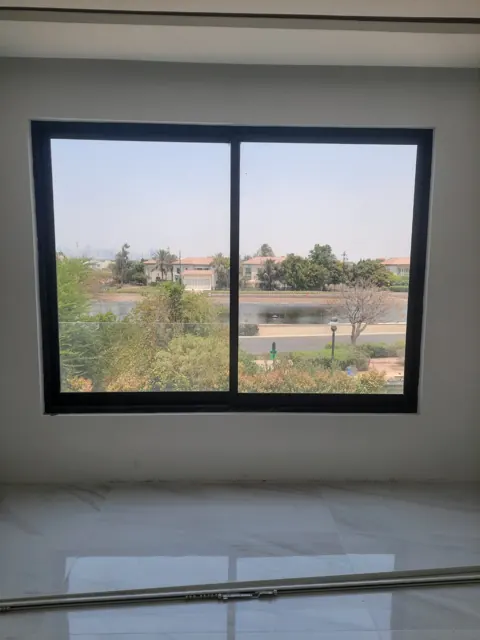 Framing the view: A broad, dark-framed window overlooking an outdoor landscape, photographed during the wider fit-out.