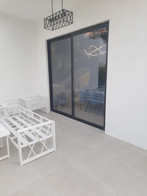 Terrace connection: Dark-framed sliding glass doors connecting an interior room with its terrace.