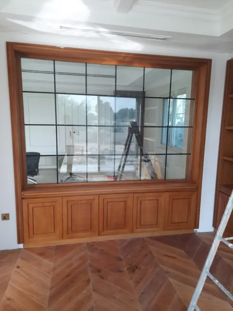 Interior glazing with grid detail: A large interior glass panel with dark grid detailing set within a timber surround.