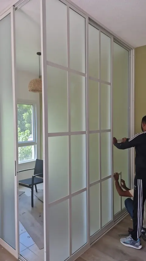 Sliding panel adjustment: Our team working at the edge of a white-framed sliding partition during installation.