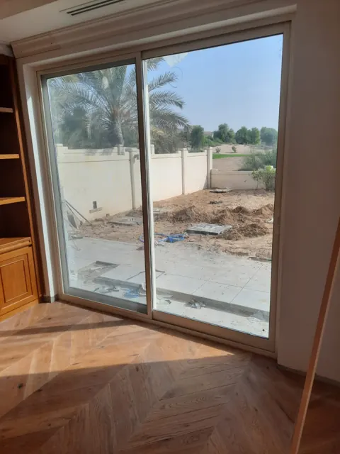 Sliding patio door: Light-coloured framing around a two-panel glazed patio opening, photographed before the exterior landscaping was finished.