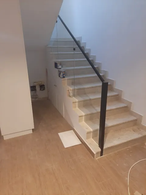 Staircase detail: A closer view of staircase glazing and its dark handrail. Surrounding finishing work was still underway in this photograph.