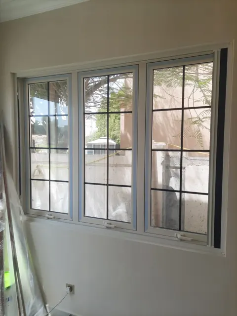 Three-panel window: Light-coloured window frames with dark grid detailing across three glazed panels.