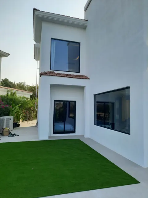 Large windows, clear views: Large glazed openings with dark framing on a two-storey villa exterior.